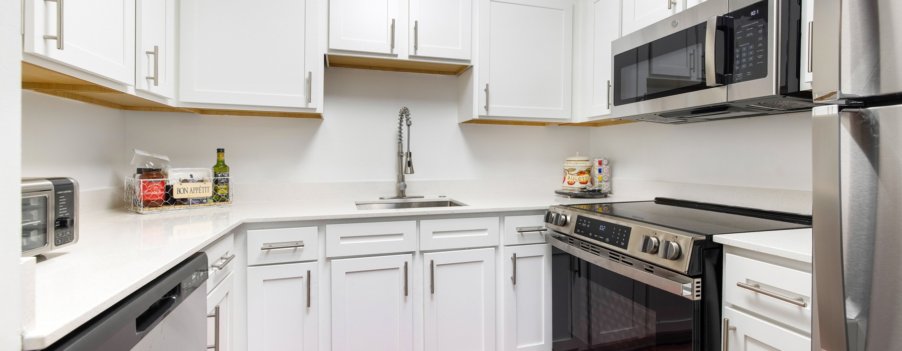 Model kitchen at The Gardens of Annapolis senior living apartments in Maryland, featuring white cabinetry and counters.