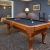 a room with a pool table and chairs